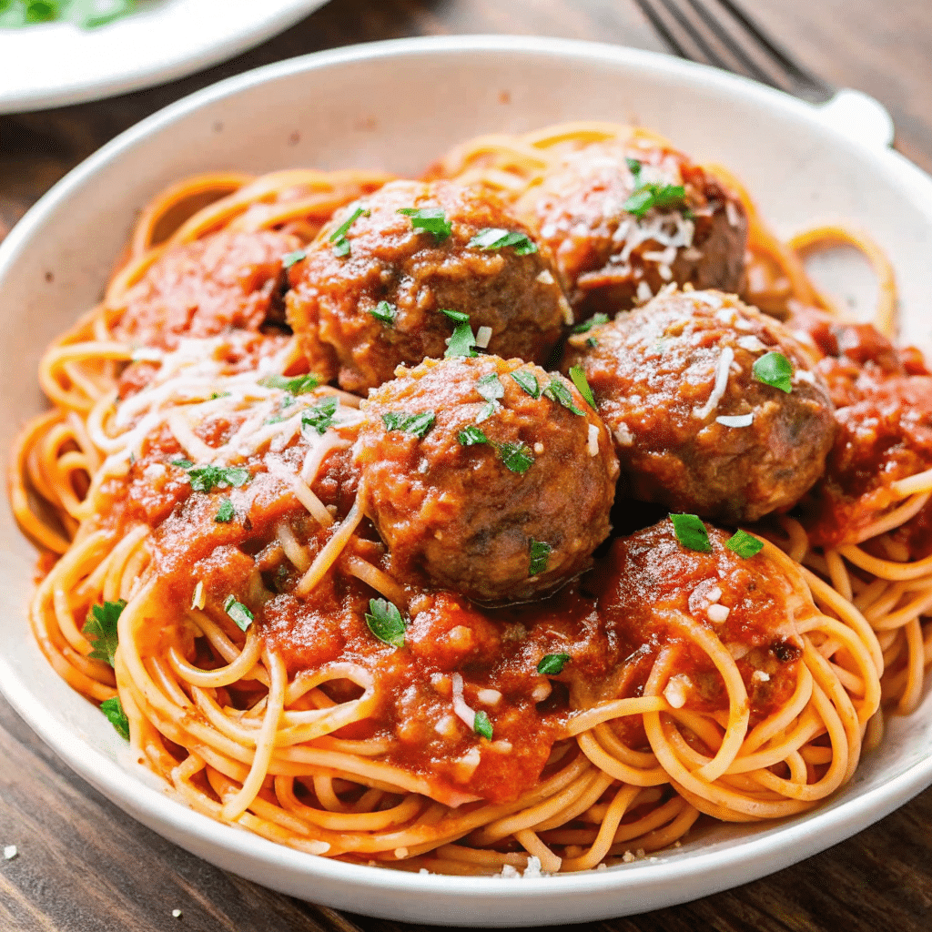 Plate of Spaghetti and Meatballs topped with rich tomato sauce, freshly baked meatballs, and grated Parmesan cheese.
