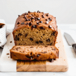 Freshly baked Peanut Butter Banana Bread sliced on a wooden board with visible chocolate chips and a soft, moist texture