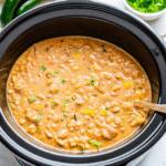 Creamy Crock Pot White Chicken Chili served in a bowl with shredded chicken, white beans, corn, and green chiles topped with cilantro.