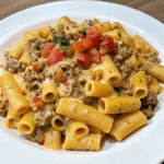 Creamy Cheesy Beef Rigatoni served in a bowl with seasoned ground beef, rich cheese sauce, and fresh tomato garnish.