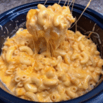 Creamy Buffalo Chicken Mac And Cheese topped with melted cheddar and mozzarella in a serving bowl.