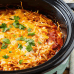 Crockpot Chicken Enchilada Casserole served in a slow cooker, topped with melted cheese and tortilla layers.