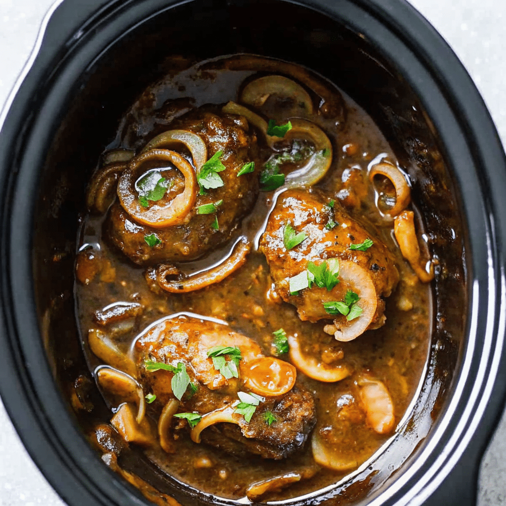 Slow cooker salisbury steak patties in rich brown gravy served over mashed potatoes