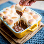Golden toasted marshmallows over melted chocolate in a warm Smores Dip served with graham crackers.