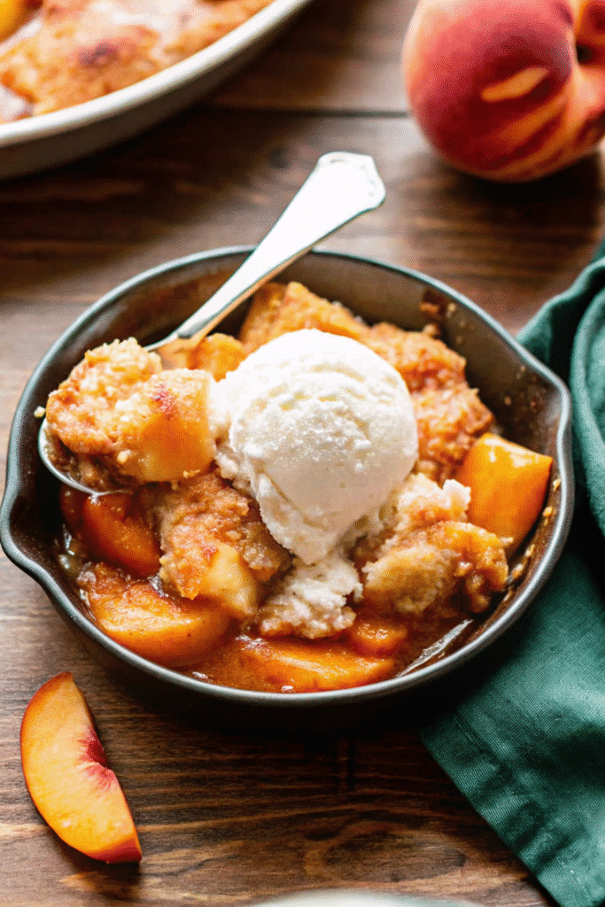 Homemade Crock Pot Peach Cobbler bubbling with fresh peaches and sugar under a soft biscuit-style topping.