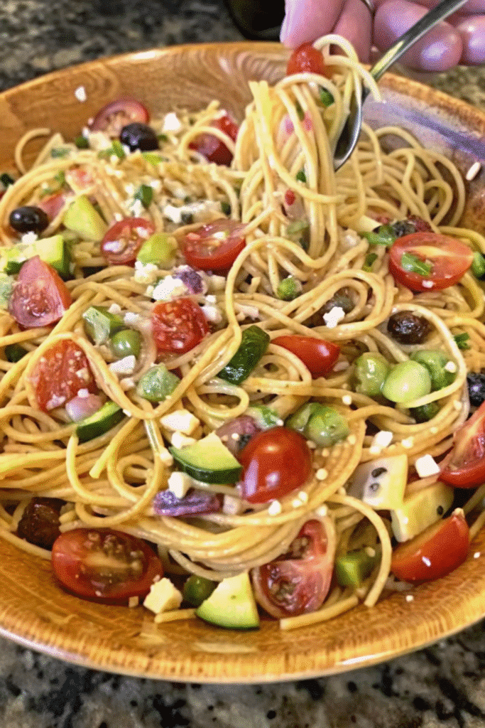 Chilled California Spaghetti Salad featuring colorful vegetables, spaghetti noodles, cheese, and herbs in a large serving bowl.