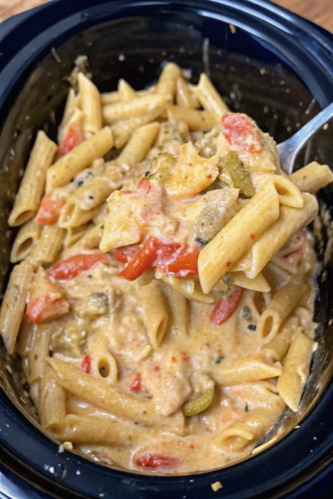 Close-up of Creamy Crockpot Chicken Fajita Pasta topped with melted Mexican cheese and sliced bell peppers.