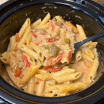 Creamy Crockpot Chicken Fajita Pasta served in a bowl with shredded chicken, colorful bell peppers, and melted cheese.