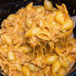 Creamy Crockpot BBQ Chicken Mac And Cheese with shredded chicken, melted cheddar and mozzarella, and pasta shells coated in smoky barbecue sauce.