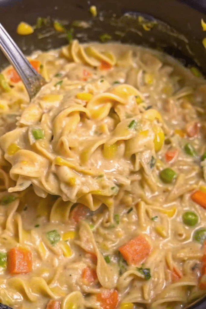 Close-up of Crockpot Creamy Chicken served in a bowl with creamy broth, noodles, and vegetables
