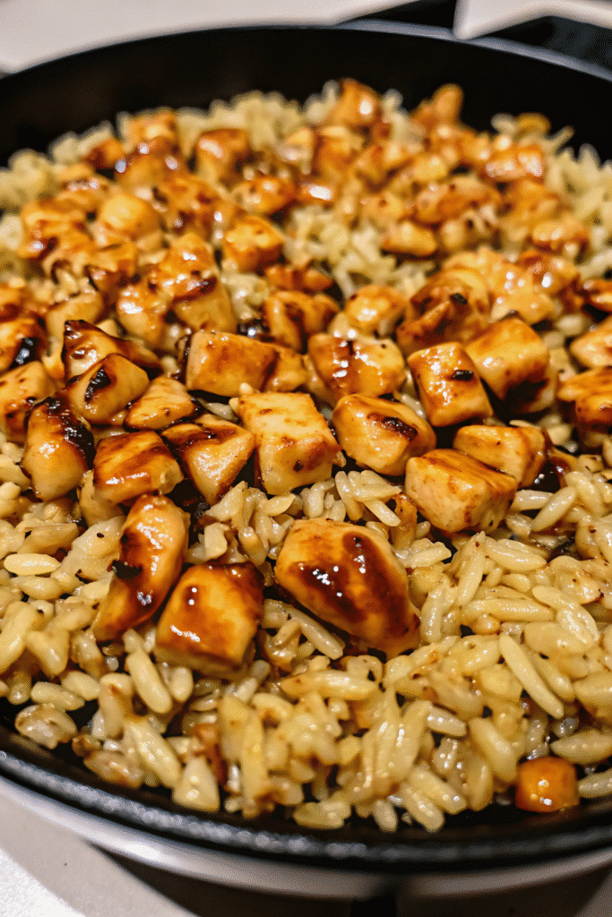 Skillet of One Pan Bold Honey BBQ Chicken Rice garnished with green onions and rich BBQ glaze