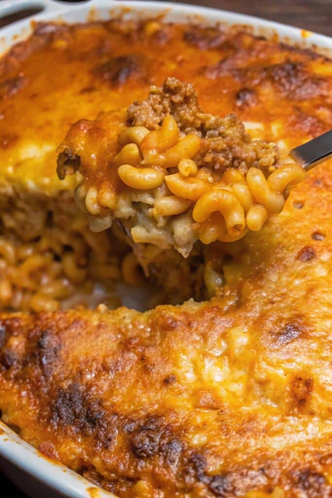 Slice of Cheesy Mac And Cheese Lasagna showing layers of cheesy pasta, ground beef sauce, and gooey melted cheese