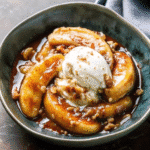 Bananas Foster served warm over vanilla ice cream with caramel sauce and walnuts in a skillet