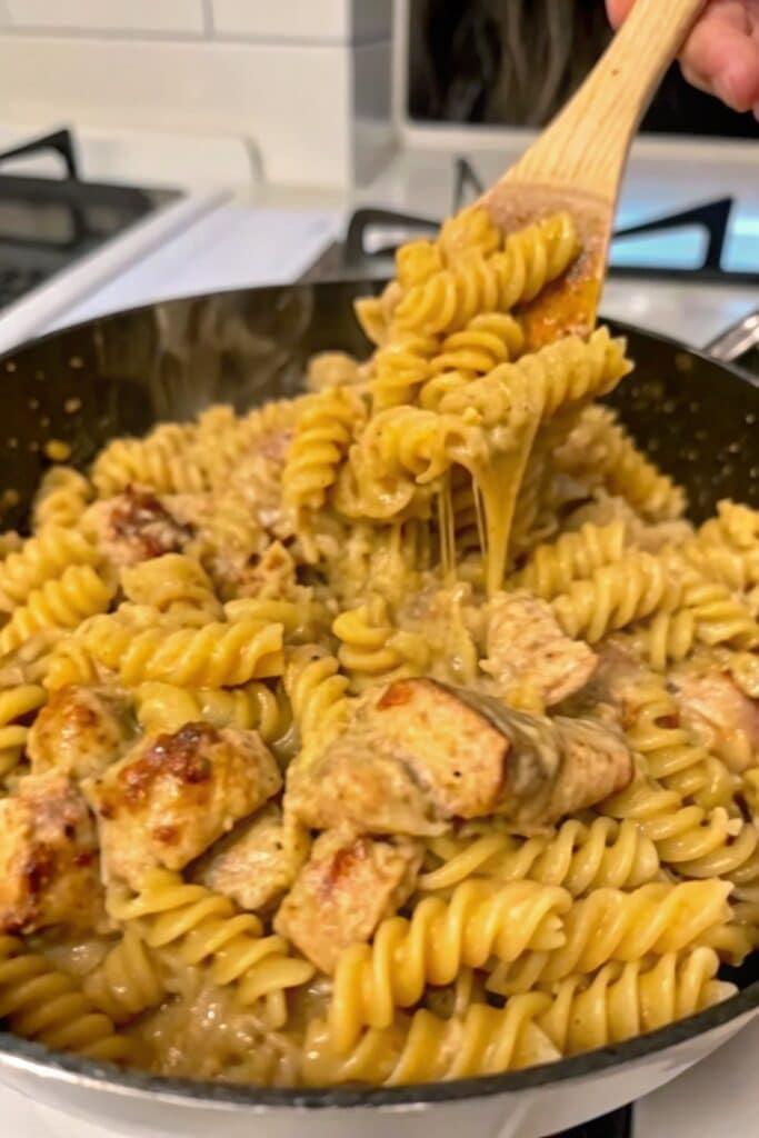 One Pan Chicken Cheddar Pasta 3 Golden cheddar-coated pasta mixed with seasoned chicken and onions in a skillet, ready to serve for a family dinner.