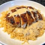 Creamy Cajun Chicken and Rice served with sliced seasoned chicken over fluffy white rice and topped with rich Parmesan cream sauce in a skillet-style presentation.
