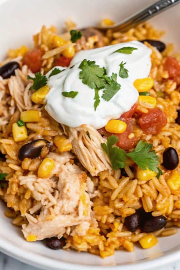 Chicken Burrito Bowl Bake 3 Close-up of Chicken Burrito Bowl Bake with shredded chicken, black beans, corn, cheese, and cilantro garnish.