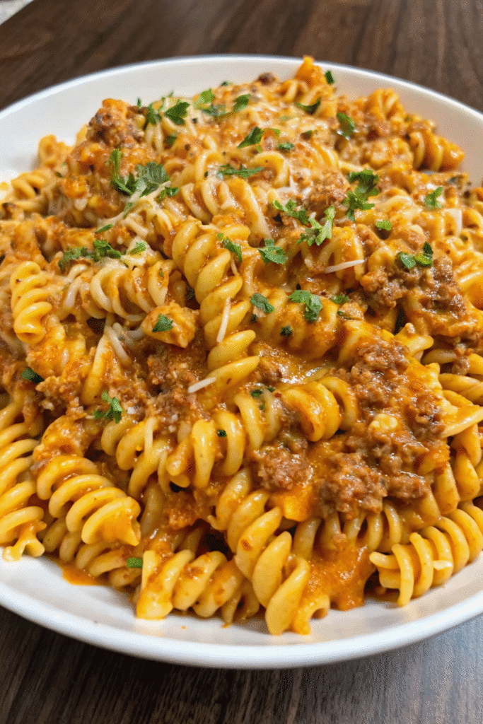 Close-up of Cajun Ground Beef Rotini with spiral pasta, seasoned beef crumbles, creamy Parmesan sauce, and chopped parsley on top.