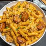 Buffalo Chicken And Smoked Sausage Penne served in a skillet with tender chicken, smoked sausage slices, creamy buffalo cheese sauce, and penne pasta.