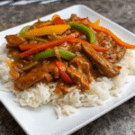 Homemade Pepper Chicken with Rice topped with seasoned chicken, sautéed bell peppers, and flavorful gravy over rice.